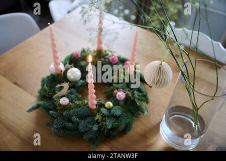 Berlin, Deutschland. Dezember 2023. Die erste Kerze brennt auf einem dekorierten Adventskranz. Annette Riedl/dpa/Alamy Live News Stockfoto