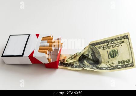 Konzept der Rauchkosten. Zigaretten auf Dollar Hintergrund. Stockfoto