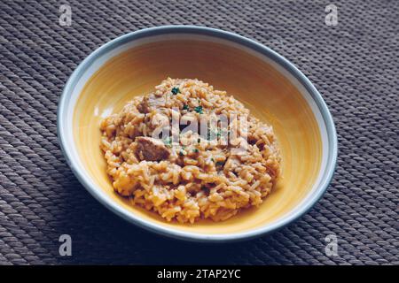 Reisgericht mit Schweinefleisch, serviert auf einem gelben Teller. Im traditionellen österreichischen serbischen Stil gekocht. Stockfoto