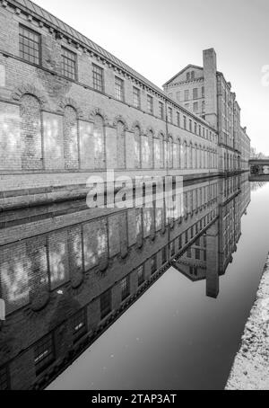 Der Kanal verläuft zwischen der New Mill (North Block) und der alten Mill Victoria Rd Saltaire Stockfoto