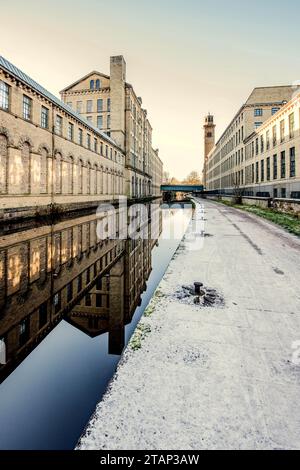 Der Kanal verläuft zwischen der New Mill (North Block) und der alten Mill Victoria Rd Saltaire Stockfoto