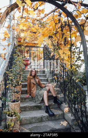 Frau sitzt auf Stufen im Herbstparkspaziergang Stockfoto