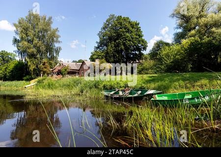 Häuser und Boote am Ufer eines wunderschönen Flusses Salaca, spektakuläre Natur, rote Sandsteinklippen aus dem Devon und üppige Wälder, Mazsalaca, Lettland Stockfoto