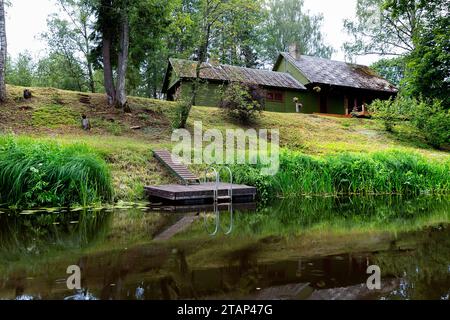 Landhaus am Ufer eines wunderschönen Salaca Flusses, spektakuläre Natur, rote Sandsteinklippen aus dem Devon und üppige Wälder, Mazsalaca, Lettland Stockfoto