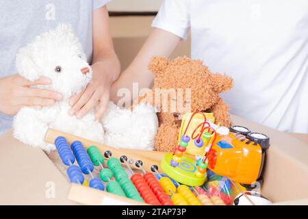 Junger Freiwilliger sammelt Spendenkiste mit Kleidung, Schulbedarf, Kinderspielzeug in der Schule, Gemeindezentrum. Ehrenamtliche Tätigkeit, Spende, Wohltätigkeit, Hilfe für Stockfoto