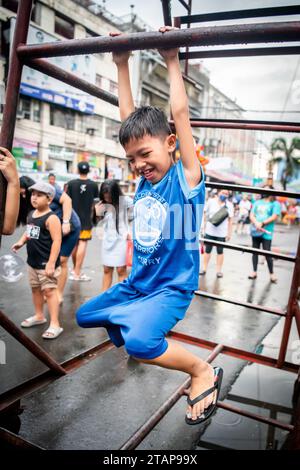 Ein junger philippinischer Junge spielt auf einem Metallrahmen in Tondo, Manila, den Philippinen. Stockfoto