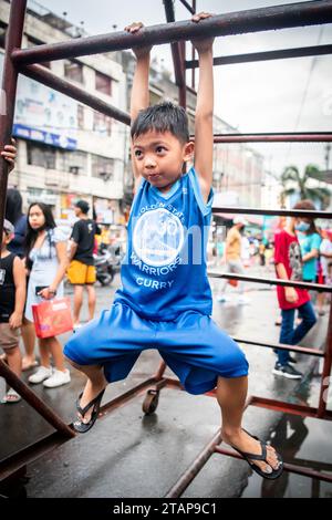 Ein junger philippinischer Junge spielt auf einem Metallrahmen in Tondo, Manila, den Philippinen. Stockfoto