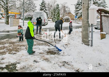 Zbysov, Tschechische Republik. Dezember 2023. Eine Familie entfernt Schnee von einem Pflaster in Zbysov, Brünn, Tschechische Republik, 2. Dezember 2023. Quelle: Patrik Uhlir/CTK Photo/Alamy Live News Stockfoto