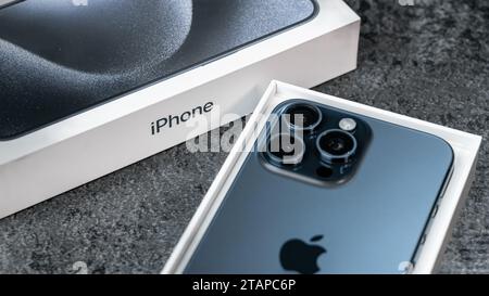 Jurmala, Lettland - 30 11 2023: Close-up Box und neues Smartphone Apple iPhone 15 Pro Max in Blue Titanium Farbe auf grauem Tisch. Stockfoto