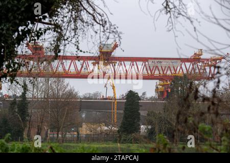 Harefield, Großbritannien. Dezember 2023. Dominique der riesige, orange Trägerkran HS2, der den nächsten Teil des Colne Valley Viaduct in Harefield baut, der neue Hochgeschwindigkeitszüge von London nach Birmingham bringen wird. Das umstrittene Hochgeschwindigkeitsbahnprojekt ist nach wie vor sehr über dem Budget. Die nördliche Phase 2 von HS2 wurde von Rishi Sunak abgesagt, aber es gibt jetzt Bedenken von Bewohnern nördlich von Birmingham, dass, wenn Labour im nächsten Jahr gewählt wird, Keir Starmer von Bürgermeister Andy Burnham angeregt wurde, Phase 2 wiederbeleben könnte. Es wurde berichtet, dass einige Personen auf der unterdrückten HS2-Strecke b Stockfoto