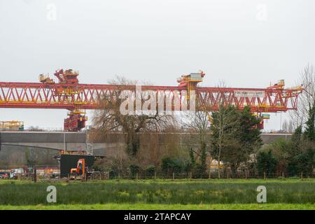 Harefield, Großbritannien. Dezember 2023. Dominique der riesige, orange Trägerkran HS2, der den nächsten Teil des Colne Valley Viaduct in Harefield baut, der neue Hochgeschwindigkeitszüge von London nach Birmingham bringen wird. Das umstrittene Hochgeschwindigkeitsbahnprojekt ist nach wie vor sehr über dem Budget. Die nördliche Phase 2 von HS2 wurde von Rishi Sunak abgesagt, aber es gibt jetzt Bedenken von Bewohnern nördlich von Birmingham, dass, wenn Labour im nächsten Jahr gewählt wird, Keir Starmer von Bürgermeister Andy Burnham angeregt wurde, Phase 2 wiederbeleben könnte. Es wurde berichtet, dass einige Personen auf der unterdrückten HS2-Strecke b Stockfoto