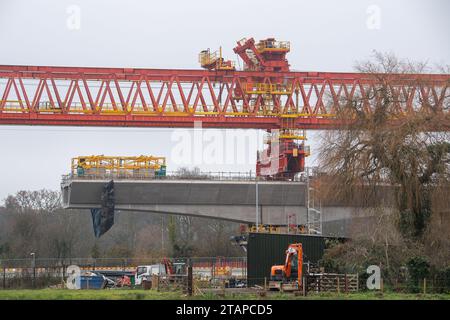 Harefield, Großbritannien. Dezember 2023. Dominique der riesige, orange Trägerkran HS2, der den nächsten Teil des Colne Valley Viaduct in Harefield baut, der neue Hochgeschwindigkeitszüge von London nach Birmingham bringen wird. Das umstrittene Hochgeschwindigkeitsbahnprojekt ist nach wie vor sehr über dem Budget. Die nördliche Phase 2 von HS2 wurde von Rishi Sunak abgesagt, aber es gibt jetzt Bedenken von Bewohnern nördlich von Birmingham, dass, wenn Labour im nächsten Jahr gewählt wird, Keir Starmer von Bürgermeister Andy Burnham angeregt wurde, Phase 2 wiederbeleben könnte. Es wurde berichtet, dass einige Personen auf der unterdrückten HS2-Strecke b Stockfoto