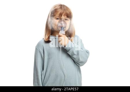 Kleines Mädchen, das eine tragbare Inhalatormaske mit Dampfnebel auf weißem Hintergrund verwendet Stockfoto