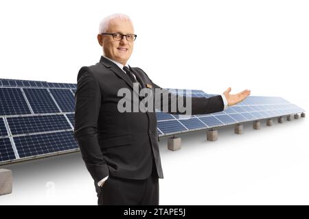 Reifer Mann in einem schwarzen Anzug, der Solarpaneele isoliert auf weißem Hintergrund präsentiert Stockfoto