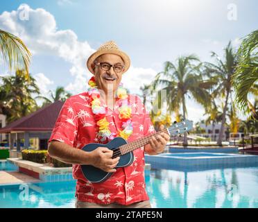 Reifer männlicher Tourist, der Ukulele am Swimmingpool spielt Stockfoto