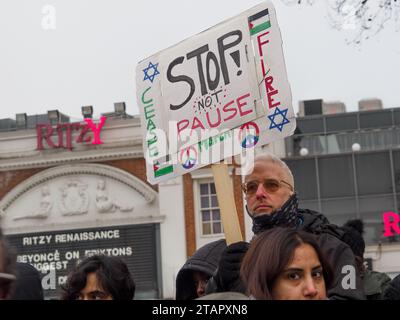 London, Großbritannien. Dezember 2023. Am Ende eines waffenstillstandsmarsches in Gaza zu einer Kundgebung in Brixton umzingelte eine Menschenmenge einen Polizeiwagen mit einem jungen Teenager, der wegen eines angeblich antisemitischen Plakats verhaftet wurde und rief: „Lass sie gehen!“ Und den Van daran hindern zu gehen. Die Polizei stritt sich etwa 45 Minuten lang mit den Demonstranten und brachte schließlich fast hundert Polizisten ein, die die Menge zurück auf den Bürgersteig drängten, damit der Van abfahren konnte. Peter Marshall/Alamy Live News Stockfoto