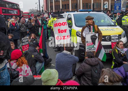 London, Großbritannien. Dezember 2023. Am Ende eines waffenstillstandsmarsches in Gaza zu einer Kundgebung in Brixton umzingelte eine Menschenmenge einen Polizeiwagen mit einem jungen Teenager, der wegen eines angeblich antisemitischen Plakats verhaftet wurde und rief: „Lass sie gehen!“ Und den Van daran hindern zu gehen. Die Polizei stritt sich etwa 45 Minuten lang mit den Demonstranten und brachte schließlich fast hundert Polizisten ein, die die Menge zurück auf den Bürgersteig drängten, damit der Van abfahren konnte. Peter Marshall/Alamy Live News Stockfoto