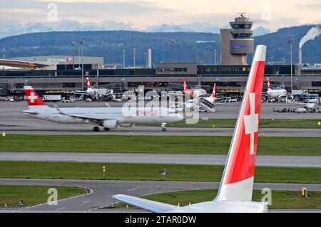 Vertikales Heck eines Airbusses der Swiss International Air Lines mit dem Schweizer Kreuz, hinter einem Flugzeug der Swiss Airlines, das am Flughafen Zürich startet Stockfoto