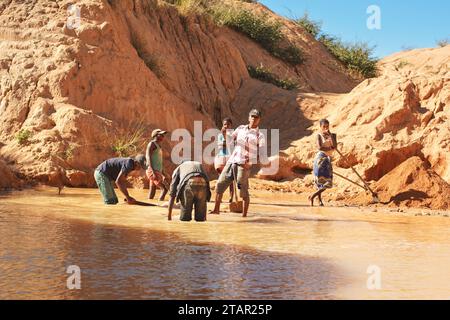 Ilakaka, Madagaskar - 30. April 2019: Gruppe unbekannter madagassischer Männer, die an einem sonnigen Tag mit Schaufeln Saphir in der oberflächennahen Seegrube abbauen, trockener roter Boden Stockfoto