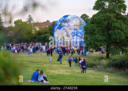 Brünn, Tschechien - 12. Juli 2020: Menschen, die vor dem aufblasbaren Erdmodell laufen, das auf einer grünen Wiese in der Nähe des Planetariumparks aufgestellt wurde Stockfoto