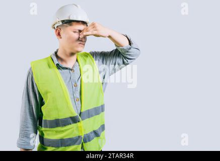 Mann Ingenieur bedeckt ihre Nase vor einem schlechten Geruch isoliert isoliert. Verärgerter junger Ingenieur, der ihre Nase isoliert hält Stockfoto