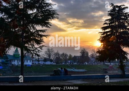 Srinagar, Indien. Dezember 2023. Kaschmirmädchen ruhen sich während des Sonnenuntergangs in Srinagar, der Sommerhauptstadt von Jammu und Kaschmir, am Ufer des Flusses Jehlum aus. (Foto: Saqib Majeed/SOPA Images/SIPA USA) Credit: SIPA USA/Alamy Live News Stockfoto