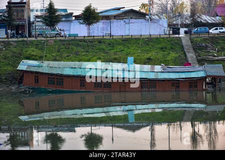 Srinagar, Indien. Dezember 2023. In Srinagar, der Sommerhauptstadt von Jammu und Kaschmir, ist ein teilweise untergetauchtes Wohnboot im Fluss Jehlum zu sehen. (Foto: Saqib Majeed/SOPA Images/SIPA USA) Credit: SIPA USA/Alamy Live News Stockfoto