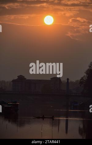 Srinagar, Indien. Dezember 2023. Ein Bootsmann, der während des Sonnenuntergangs in Srinagar, der Sommerhauptstadt von Jammu und Kaschmir, Passagiere über den Fluss Jehlum transportierte. (Foto: Saqib Majeed/SOPA Images/SIPA USA) Credit: SIPA USA/Alamy Live News Stockfoto