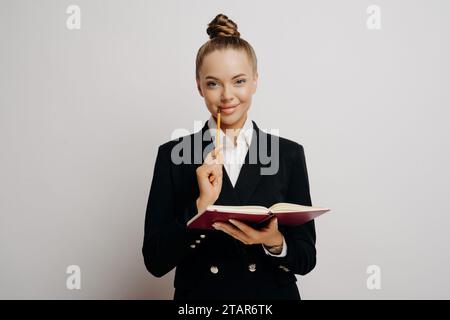 Fleißige junge Frau in Geschäftskleidung, die Notizen macht, Fokus und akademisches Engagement zeigt Stockfoto