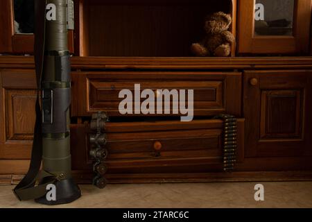 Ein Granatwerfer steht auf dem Boden, Maschinengewehrgürtel mit Patronen hängen an einer Kiste in einer Wohnung in der Ukraine, Waffen werden in einem Haus gelagert Stockfoto