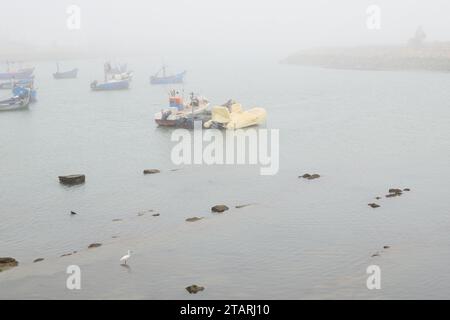 Unbearbeitetes Foto von Fischerbooten in einem Hafen bei nebeligem Wetter Stockfoto