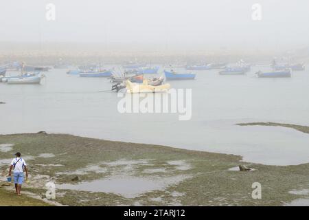 Unbearbeitetes Foto von Fischerbooten in einem Hafen bei nebeligem Wetter Stockfoto