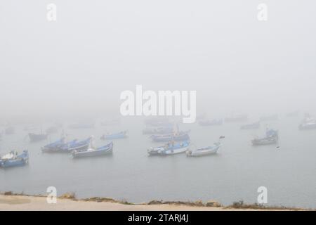 Unbearbeitetes Foto von Fischerbooten in einem Hafen bei nebeligem Wetter Stockfoto