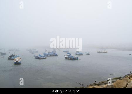 Unbearbeitetes Foto von Fischerbooten in einem Hafen bei nebeligem Wetter Stockfoto