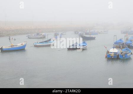 Unbearbeitetes Foto von Fischerbooten in einem Hafen bei nebeligem Wetter Stockfoto