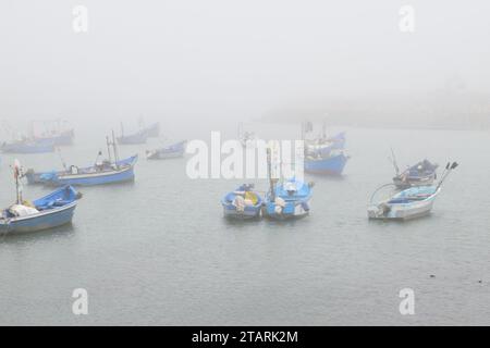 Unbearbeitetes Foto von Fischerbooten in einem Hafen bei nebeligem Wetter Stockfoto