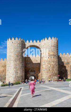 Frau, die auf die Stadtmauern und Befestigungsanlagen in der spanischen Stadt Avila in der autonomen Gemeinde Kastilien und León Spanien zugeht Stockfoto