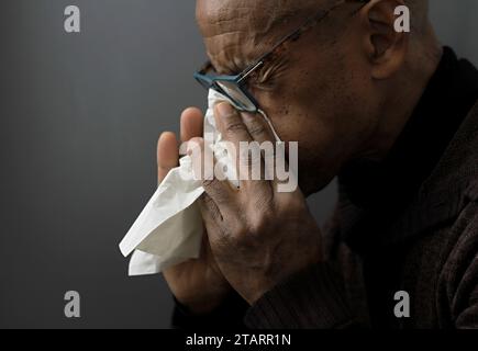 Fangen der Erkältung und Grippe Mann, der Nase bläst, nachdem er eine Erkältung mit grauem Hintergrund mit Leuten Stock Foto gefangen hat Stockfoto