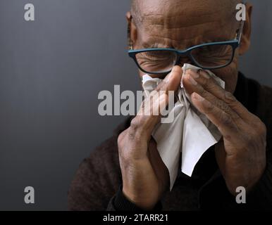 Fangen der Erkältung und Grippe Mann, der Nase bläst, nachdem er eine Erkältung mit grauem Hintergrund mit Leuten Stock Foto gefangen hat Stockfoto