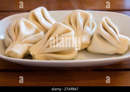 Reisen Sie nach Georgien - ein Teil der gekochten Khinkali (georgianische Knödel) Nahaufnahme auf einem Teller auf einem Holztisch im lokalen Café in Batumi City Stockfoto