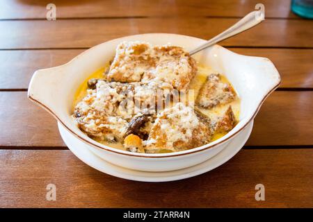 Reisen Sie nach Georgien - Portion Chkmeruli (georgisches Gericht, Hühnchenstücke in cremiger Knoblauchsoße gebraten) in einer Schüssel auf Holztisch im lokalen Café in Batumi Stockfoto