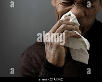 Fangen der Erkältung und Grippe Mann, der Nase bläst, nachdem er eine Erkältung mit grauem Hintergrund mit Leuten Stock Foto gefangen hat Stockfoto