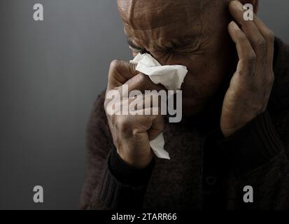 Fangen der Erkältung und Grippe Mann, der Nase bläst, nachdem er eine Erkältung mit grauem Hintergrund mit Leuten Stock Foto gefangen hat Stockfoto