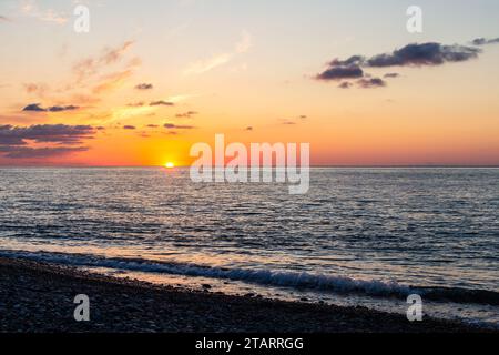 Reisen Sie nach Georgia - Blick auf den Sonnenuntergang am Horizont vom Kiesstrand in Batumi am Herbstabend Stockfoto
