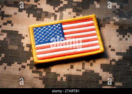 Nahaufnahme eines amerikanischen Flaggenpflasters auf einem Hintergrund militärischer Tarnung, 2023, USA Stockfoto