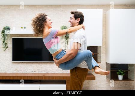 Fröhliches junges Paar, das sich zu Hause umarmt Stockfoto