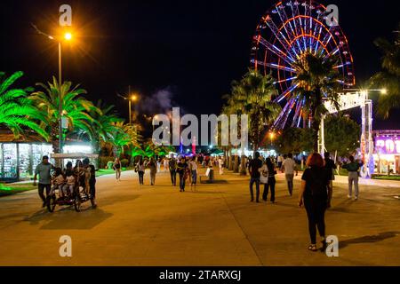 Batumi, Georgien – 16. September 2023: Die Menschen spazieren auf der Promenade in der Nähe des Batumi Festivals im Miracle Park in der Herbstnacht in Batumi City. Stockfoto