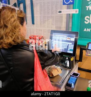Frau, die an einer automatisierten Selbstkasse in einem Whole Foods-Supermarkt in San Francisco, Kalifornien, auscheckt; über das Tastenfeld. Stockfoto