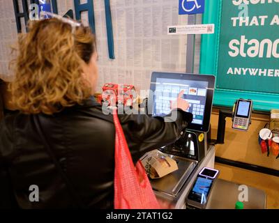 Frau, die an einer automatisierten Selbstkasse in einem Whole Foods-Supermarkt in San Francisco, Kalifornien, auscheckt; über das Tastenfeld. Stockfoto