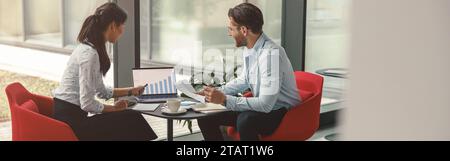 Zwei verschiedene Geschäftskollegen arbeiten gemeinsam an einem Projekt und sitzen in einem modernen Tagungsraum Stockfoto
